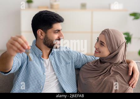 Fröhliche Muslimische Ehegatten Halten Eigenen Hausschlüssel Sitzen Drinnen Stockfoto