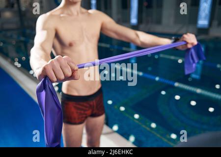 Junger, athletischer Mann, der Gummiband in den Händen hält Stockfoto