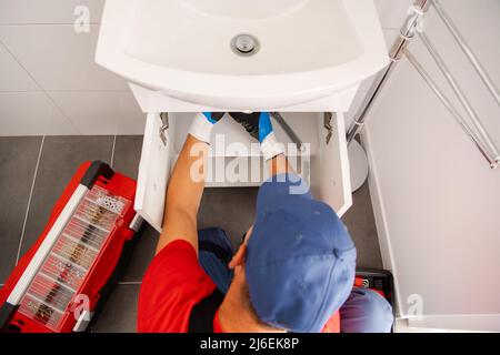 Caucasian Klempner in seinem 40s Finishing Badezimmer Waschbecken Neue Wasserentwässerung Installation Stockfoto
