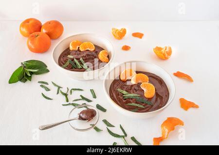 Schokoladencreme in Schüsseln mit Orangen und Minzblättern Stockfoto