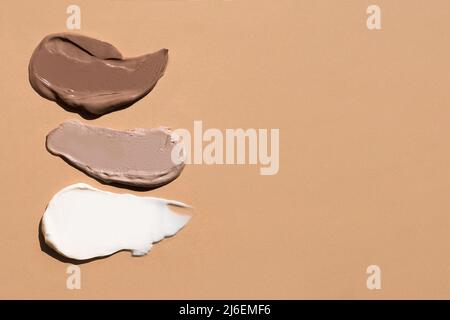 Weiße cremefarbene Textur auf einem pastellbeigen Hintergrund. Kosmetische Maske Balsam Gel. Abstriche des Fundaments für das Gesicht Stockfoto