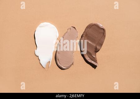 Weiße cremefarbene Textur auf einem pastellbeigen Hintergrund. Kosmetische Maske Balsam Gel. Abstriche des Fundaments für das Gesicht Stockfoto