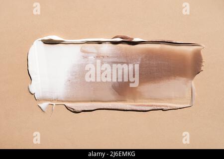 Weiße cremefarbene Textur auf einem pastellbeigen Hintergrund. Kosmetische Maske Balsam Gel. Abstriche des Fundaments für das Gesicht Stockfoto