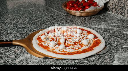 Prozess der Platzierung von Pizza mit Mozzarella, Tomaten, Käse zu Ofen in der Pizzeria, Restaurant Küche Konzept Stockfoto