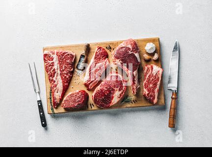 Angus Prime Fleischsteaks auf Holzschneidebrett auf grauem Beton-Hintergrund gesetzt Stockfoto