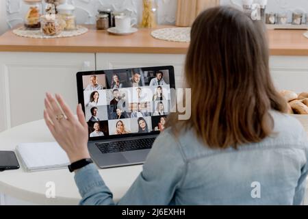 Morgendliches Meeting online. Eine junge Frau nutzt eine Anwendung auf einem Laptop, um mit Kollegen und Mitarbeitern zu kommunizieren. Videokommunikation mit viel Stockfoto