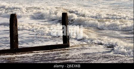 Raues Meer und verfallene Groynes am Strand von Teignmouth, South Devon. Stockfoto