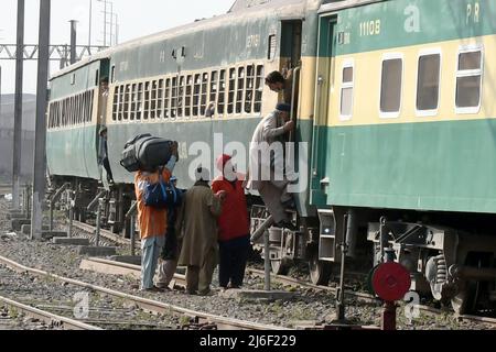 (220501) -- LAHORE, 1. Mai 2022 (Xinhua) -- Passagiere steigen vor dem Eid al-Fitr-Fest in Lahore, Pakistan, am 30. April 2022 in einen Zug an einem Bahnhof ein. (Foto von Sajjad/Xinhua) Stockfoto