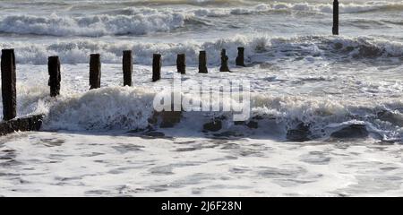 Raues Meer und verfallene Groynes am Strand von Teignmouth, South Devon. Stockfoto