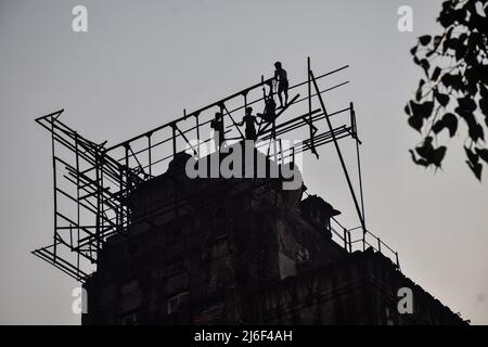 1. Mai 2022, Rajpur Sonarpur, Westbengalen, Indien: Indische Arbeiter arbeiten daran, am Internationalen Arbeitertag 2022 eine Plakatwand-Struktur auf einem Gebäude in Kalkutta zu befestigen. (Bild: © Sankhadeep Banerjee/ZUMA Press Wire) Stockfoto