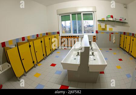 Inneneinrichtung der Badezimmer eines Kindergartens mit niedrigen Waschbecken und gelben Toilettenkabinen ohne Kinder Stockfoto