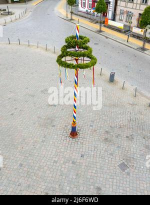 Ein bunt dekorierter Maibaum steht auf einem Marktplatz Stockfoto