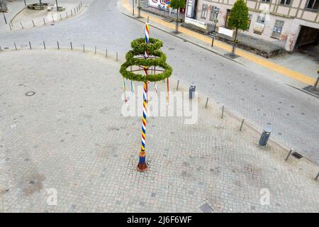 Ein bunt dekorierter Maibaum steht auf einem Marktplatz Stockfoto