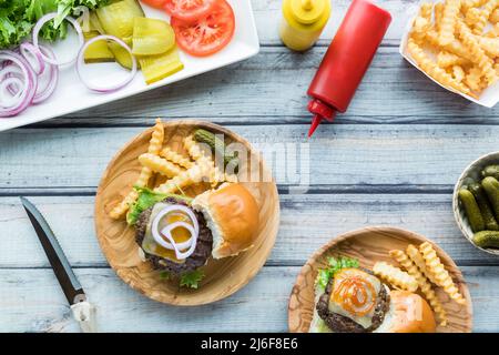 Cheeseburger-Slider mit Pommes Frites und einer Platte mit Belägen. Stockfoto