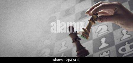 Ein Spieler checkmatet den König während eines Schachspiels: Strategiespiele und Turnierkonzept, Schachdiagramm im Hintergrund Stockfoto