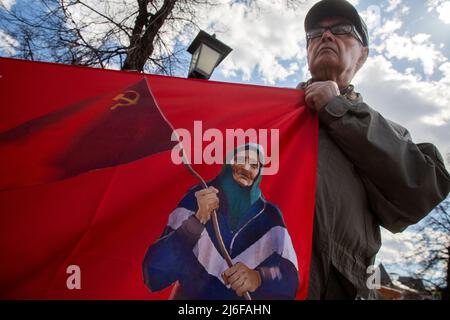 Moskau, Russland. 1.. Mai 2022. Ein Mann hält ein Transparent mit einem Porträt der ukrainischen Babuschka mit sowjetischer Flagge während einer Kundgebung der Anhänger der Kommunistischen Partei Russlands anlässlich des Internationalen Arbeitertages auf dem Teatralnaja-Platz im Zentrum von Moskau, Russland. Die Oma mit dem Roten Banner, eine ältere Frau, die auf einem Video festgehalten wurde, begrüßte ukrainische Militärangehörige mit einem sowjetischen Roten Banner und verwechselte sie mit Russisch. Quelle: Nikolay Vinokurov/Alamy Live News Stockfoto