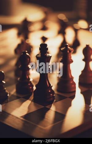 Schachfiguren auf dem Schachbrett und goldenes dunkles Licht, Schachspiele und Strategiekonzept Stockfoto