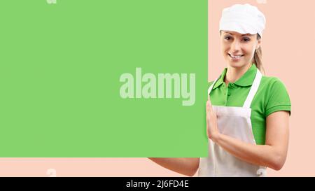 Weibliche Lebensmittelladen Assistentin mit einem grünen Schild, Lebensmitteleinkaufkonzept Stockfoto