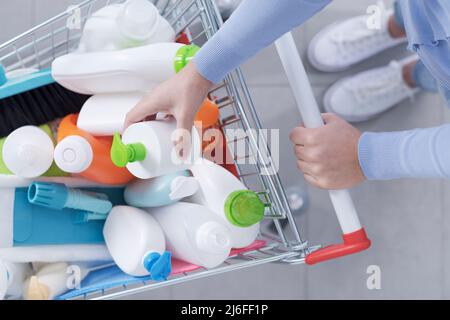 Frau, die Haushaltsgeräte und Waschmittel im Laden kauft, legt ein Produkt in den Einkaufswagen, Draufsicht Stockfoto