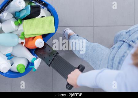 Frau, die im Laden einen Warenkorb voller Reinigungsprodukte zieht, Draufsicht Stockfoto