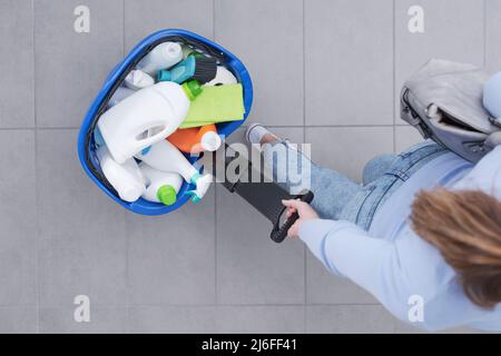 Frau, die im Laden einen Warenkorb voller Reinigungsprodukte zieht, Draufsicht Stockfoto