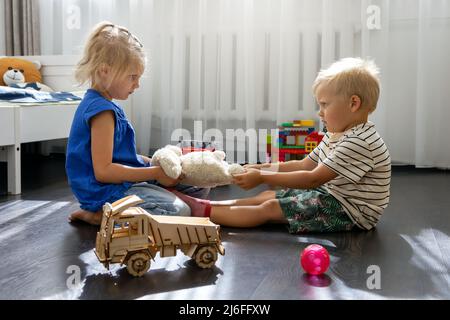 Kinder kämpfen um ein Spielzeug. Konflikt zwischen Schwester und Bruder. Geschwisterbeziehungen Stockfoto