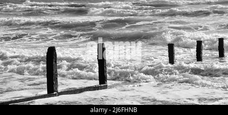 Raues Meer und verfallene Groynes am Strand von Teignmouth, South Devon. Stockfoto