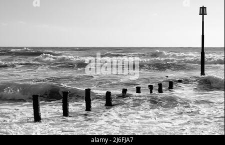 Raues Meer und verfallene Groynes am Strand von Teignmouth, South Devon. Stockfoto