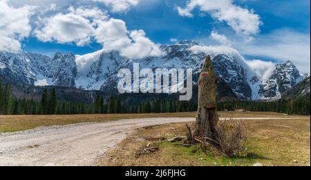 Pfad im Valromana-Tal (Fusine), im Vordergrund ein Eid-Signal, im Hintergrund Wälder, Wälder und der Mangart-Berg (Italienische Alpen) Stockfoto