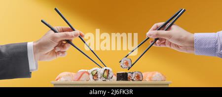 Mann und Frau essen gemeinsam Sushi mit Essstäbchen, Konzept der asiatischen Küche Stockfoto