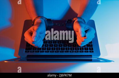 Mann in Handschellen am Computer. Konzept der Cyberkriminalität Stockfoto