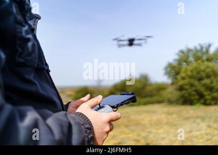 Mann, der die Kontrolle über eine Drohne übernimmt, die vor ihm fliegt. Stockfoto