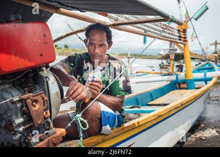 Ein indonesischer Fischer bereitet sein Boot am alten Fischerhafen in der Nähe des Dorfes Perancak, Bali, Indonesien, vor Stockfoto