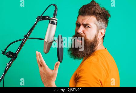 Bärtiger Mann singt im Kondensatormikrofon. Studio-Aufzeichnungen. Professioneller Sänger. Musikproduktion. Stockfoto