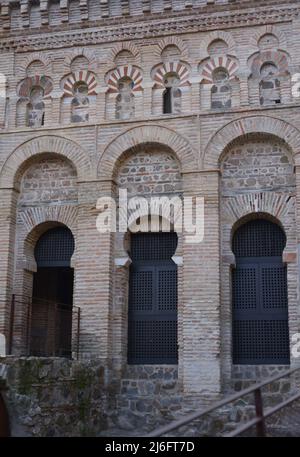 Toledo, Kastilien-La Mancha, Spanien. Schrein von Cristo de la Luz. Ehemalige Moschee, Ende des 10.. Jahrhunderts erbaut und im 12.. Jahrhundert in eine christliche Kirche umgewandelt. Architektonisches Detail der Nordwestfassade. Es ist aus Backstein gebaut und verfügt über drei halbrunde Bögen, die von Hufeisenbögen umrahmt sind, mit Öffnungen, die zum Gebetsraum führen. Der obere Teil besteht aus polygelappten Bögen, die Hufeisenbögen im Stil des Khiphals umrahmt und mit Voussoirs verziert sind. Stockfoto