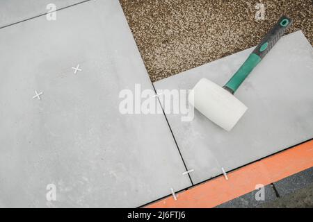 Soft Gum Made Hammer Laying auf Beton Terrasse Boden Blöcke. Bodenbelag Auf Der Terrasse Im Hinterhof. Stockfoto