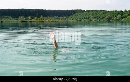 Eine Hand des ertrinkenden Mannes im Wasser, der um Hilfe bittet. Stockfoto