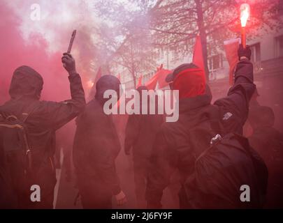 01. Mai 2022, Hessen, Frankfurt/Main: Hooded-Teilnehmer verbrennen Pyrotechnik. Am Abend demonstrierte in Frankfurt am Main ein Bündnis mehrerer linker Organisationen. Foto: Hannes P. Albert/dpa Stockfoto