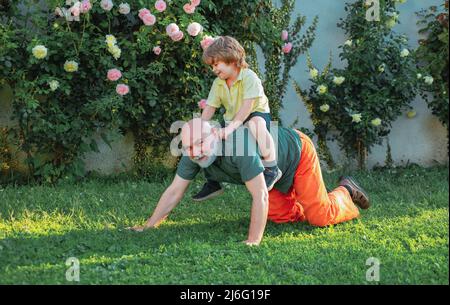 Alter Vater spielt mit Sohn - glücklicher Vatertag, Vatertag. Glücklicher älterer Mann Vater mit niedlichem kleinen Jungen Sohn, der spielt und die Kamera anschaut. Stockfoto