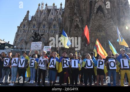 Während einer Demonstration gegen die russische Invasion in der Ukraine halten Demonstranten Flaggen und Plakate mit der Aufschrift „Save Mariupol“. Rund dreihundert Demonstranten, überwiegend Ukrainer, versammelten sich vor der berühmten Basilika Sagrada Familia in Barcelona, um einen grünen Korridor in Mariupol und Frieden für ihr Land zu fordern. Stockfoto