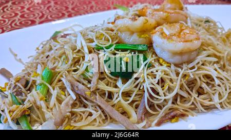 Unter Rühren Reisnudeln mit Garnelen, grünen Zwiebeln und Sojabohnen braten. Chinesisches Essen. Stockfoto