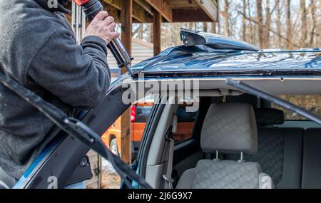 Der Arbeiter verwendet Werkzeuge, um ein defektes Fenster in einem Auto zu entfernen und durch neues Glas zu ersetzen Stockfoto