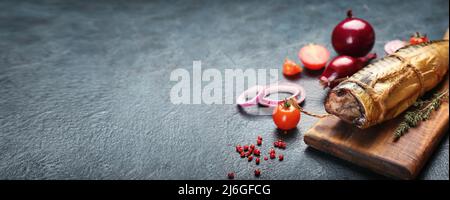 Tafel mit schmackhaftem geräuchertem Makrelenfisch und frischem Gemüse auf dunklem Hintergrund mit Platz für Text, Nahaufnahme Stockfoto