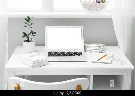 Arbeitsplatz mit modernem Laptop und Buchstaben in der Nähe des Fensters Stockfoto