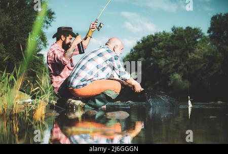 Angeln mit Großwild. Sommerwochenende. Zwei Fischer entspannen zusammen mit Bier beim Angeln am See am Morgen. Master-baiter. Wochenenden zum Angeln gemacht Stockfoto