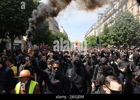 Ein maskierter Protestler hat während des traditionellen gewerkschaftsmarsches zum 1. Mai in Paris Rauchflackert. Tausende Demonstranten nahmen am 1.. Mai, dem Internationalen Arbeitertag, an der Parade zum 1. Mai in Paris Teil. Der Marsch begann vom Platz der Republik zum Platz der Nation. Stockfoto