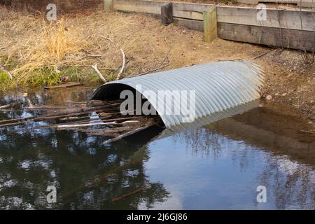 Rohrleitung unter Straße von Stream Oxbow im Park Stockfoto