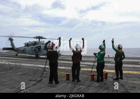 PHILIPPINISCHE SEEFAHRER (5. April 2022) signalisieren auf dem Flugdeck des Flugzeugträgers USS Abraham Lincoln (CVN 72) einen Hubschrauber vom Typ MH-60s Sea Hawk, der den „Chargers“ des Helicopter Sea Combat Squadron (HSC) 14 zugewiesen wurde. Die Abraham Lincoln Strike Group befindet sich im geplanten Einsatzgebiet der US-Flotte für 7., um die Interoperabilität durch Allianzen und Partnerschaften zu verbessern und gleichzeitig als reaktionsfähige Truppe zur Unterstützung einer freien und offenen Region im Indo-Pazifik-Raum zu dienen. (USA Navy Foto von Mass Communication Specialist 3. Class Javier Reyes) Stockfoto