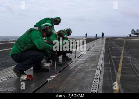 PHILIPPINISCHE SEE (5. April 2022) Matrosen stecken Knöpfe in ein Katapult (Track) auf dem Flugdeck des Nimitz-Klasse Flugzeugträgers USS Abraham Lincoln (CVN 72). Die Abraham Lincoln Strike Group befindet sich im geplanten Einsatzgebiet der US-Flotte für 7., um die Interoperabilität durch Allianzen und Partnerschaften zu verbessern und gleichzeitig als reaktionsfähige Truppe zur Unterstützung einer freien und offenen Region im Indo-Pazifik-Raum zu dienen. (USA Navy Foto von Mass Communication Specialist 3. Class Javier Reyes) Stockfoto