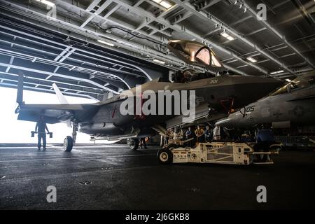 PHILIPPINISCHE SEEFAHRER (5. April 2022) transportieren einen F-35C Lightning II, der den "Black Knights" of Marine Fighter Attack Squadron (VMFA) 314 zugewiesen wurde, in die Hangarbucht des Flugzeugträgers USS Abraham Lincoln (CVN 72) der Nimitz-Klasse. Die Abraham Lincoln Strike Group befindet sich im geplanten Einsatzgebiet der US-Flotte für 7., um die Interoperabilität durch Allianzen und Partnerschaften zu verbessern und gleichzeitig als reaktionsfähige Truppe zur Unterstützung einer freien und offenen Region im Indo-Pazifik-Raum zu dienen. (USA Navy Foto von Mass Communication Specialist 3. Klasse Thaddeus Berry) Stockfoto